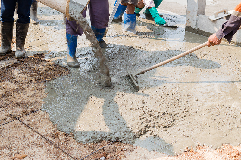 workers pouring concrete and spreading it onto dirt