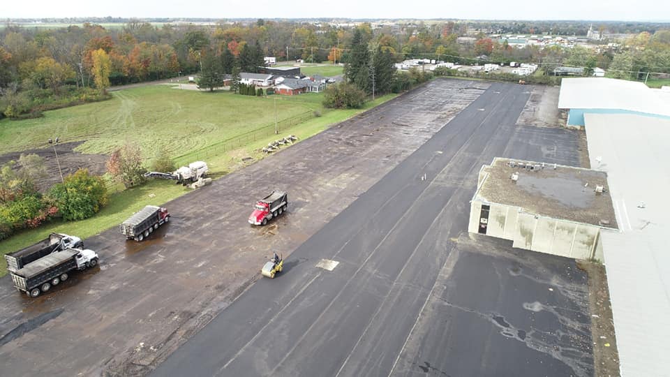 R&R Asphalt midway through laying new asphalt and paving a parking lot, an asphalt roller is seen working