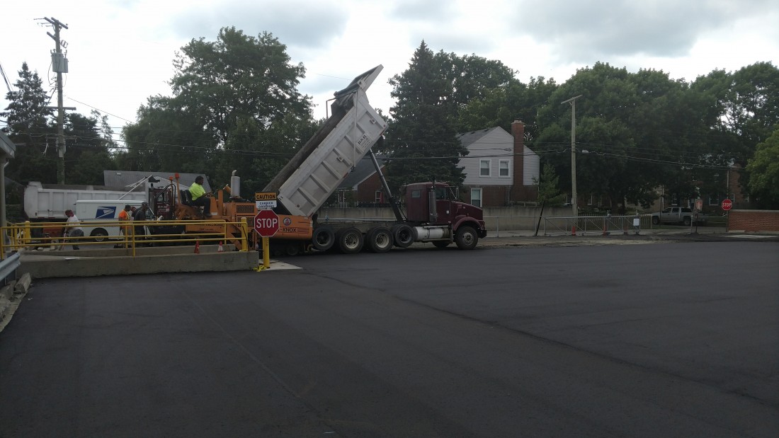 R&R Asphalt dump truck unloading asphalt into an asphalt laying vehicle