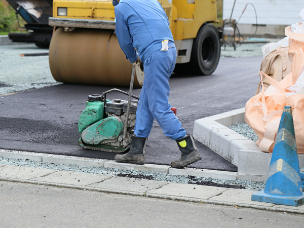 paving contractors using handheld and driven asphalt rollers to maintain a new driveway